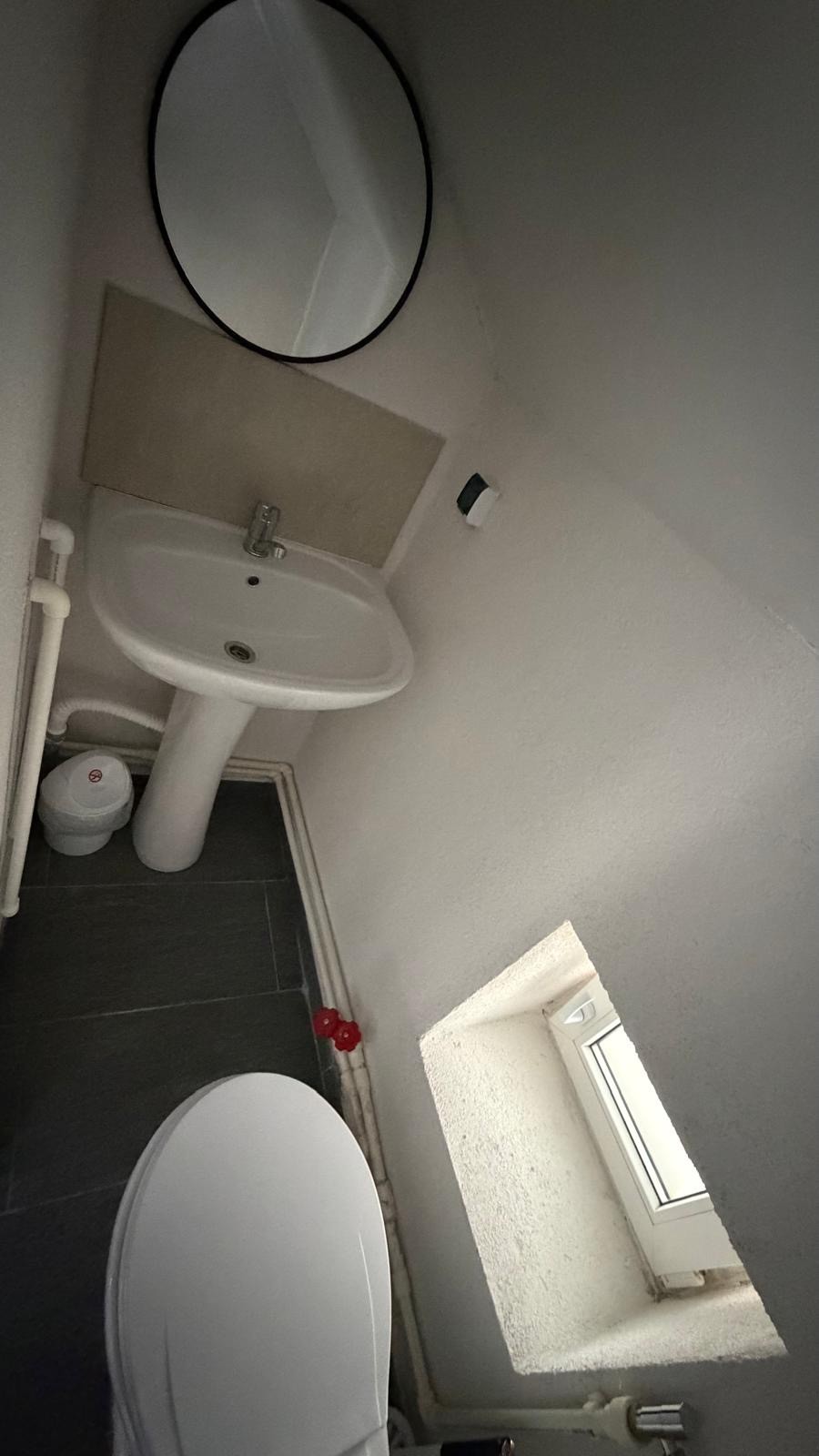 Baie privata cu oglinda rotunda si chiuveta moderna la Radel House Costinesti
