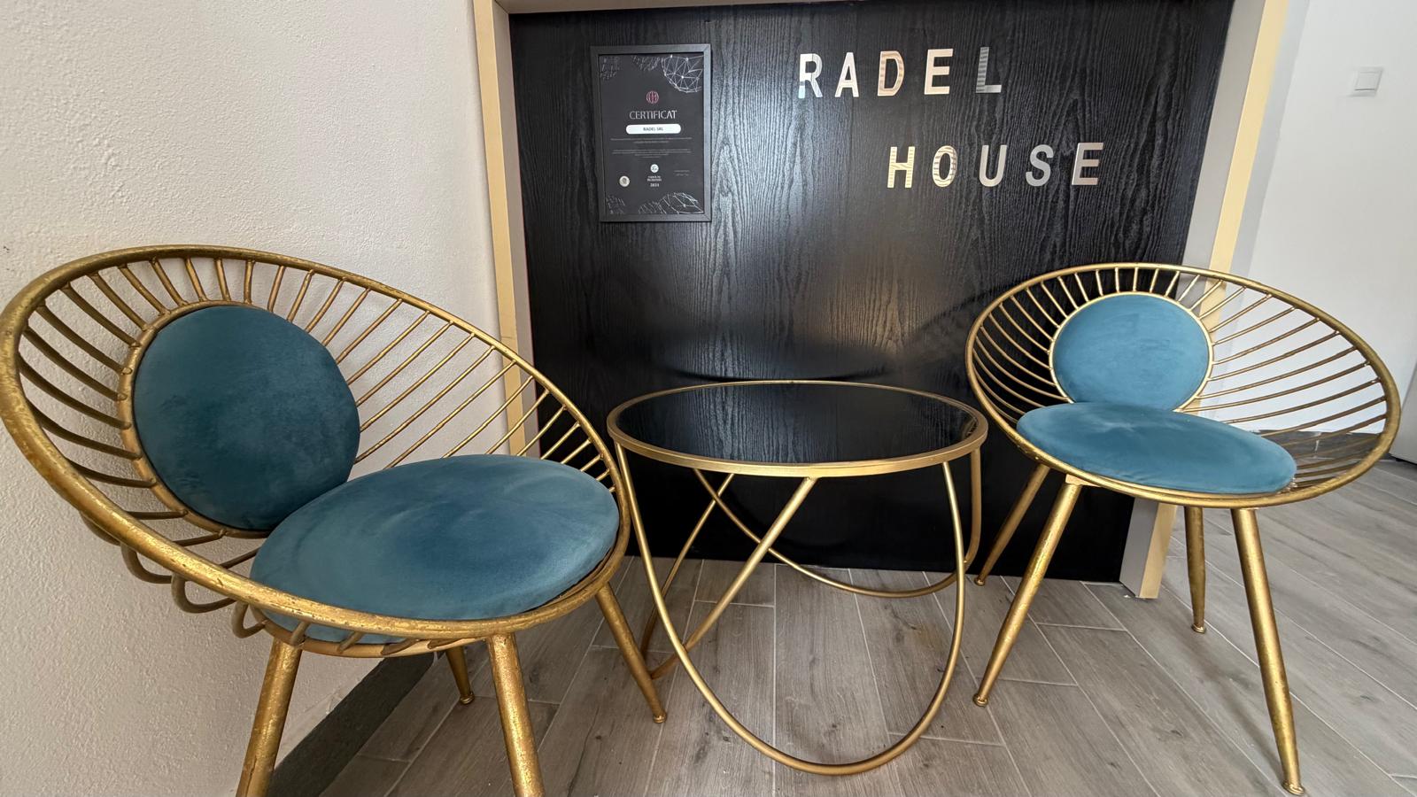Zona de asteptare cu fotolii aurii si masa rotunda in fata peretelui brandat Radel House